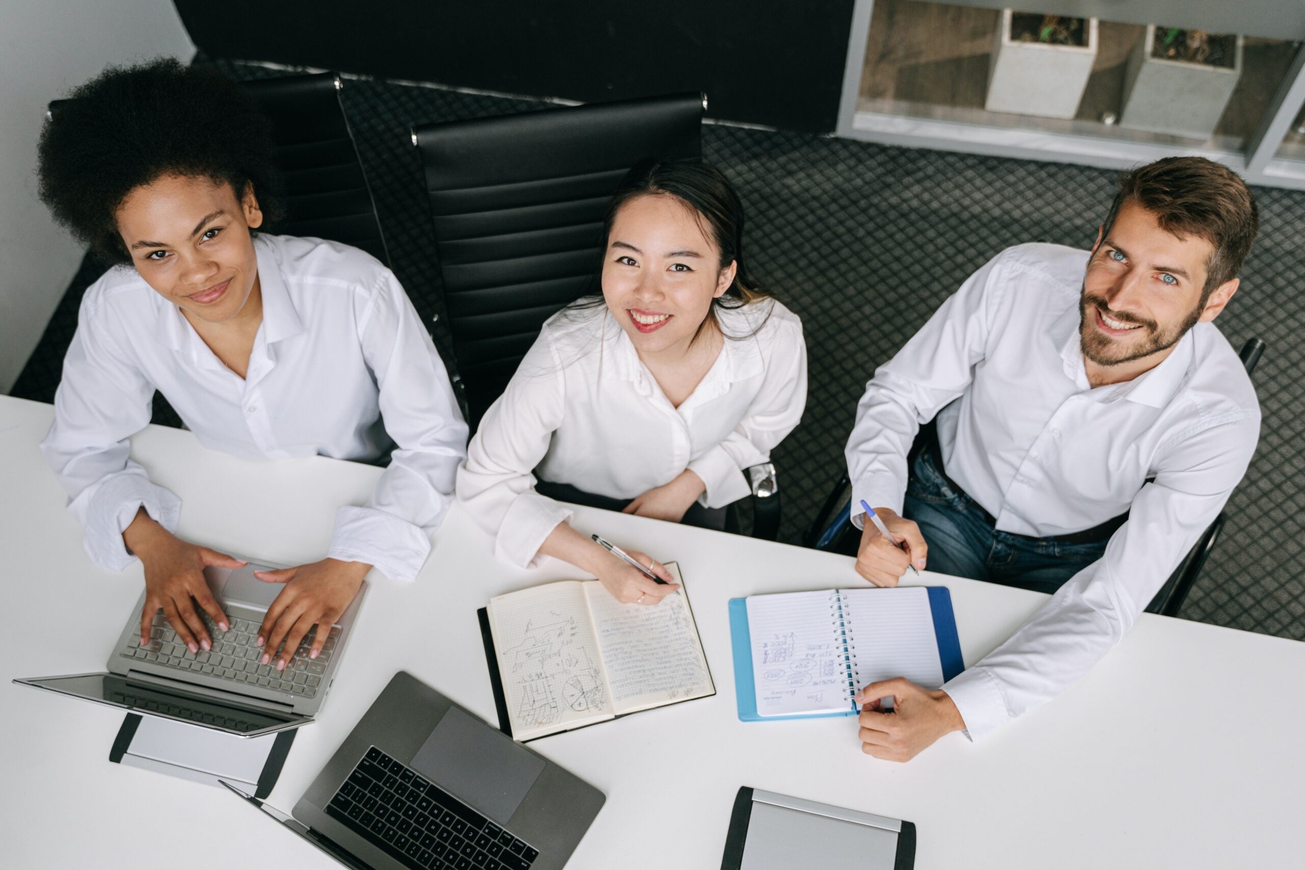 a diverse trio of colleagues look upwards from an office space desk