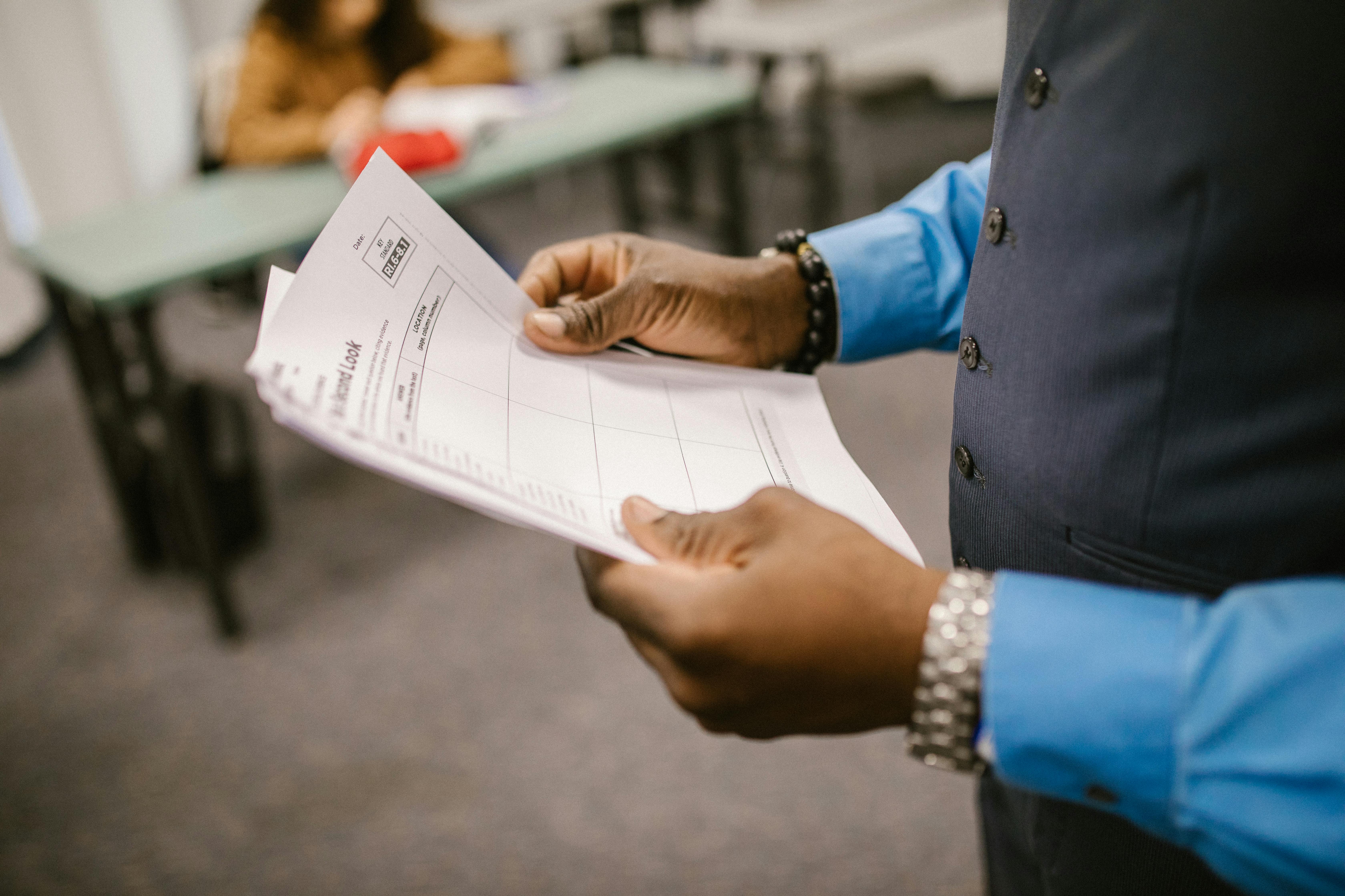 a person's hands holding a stack of papers in an office setting
