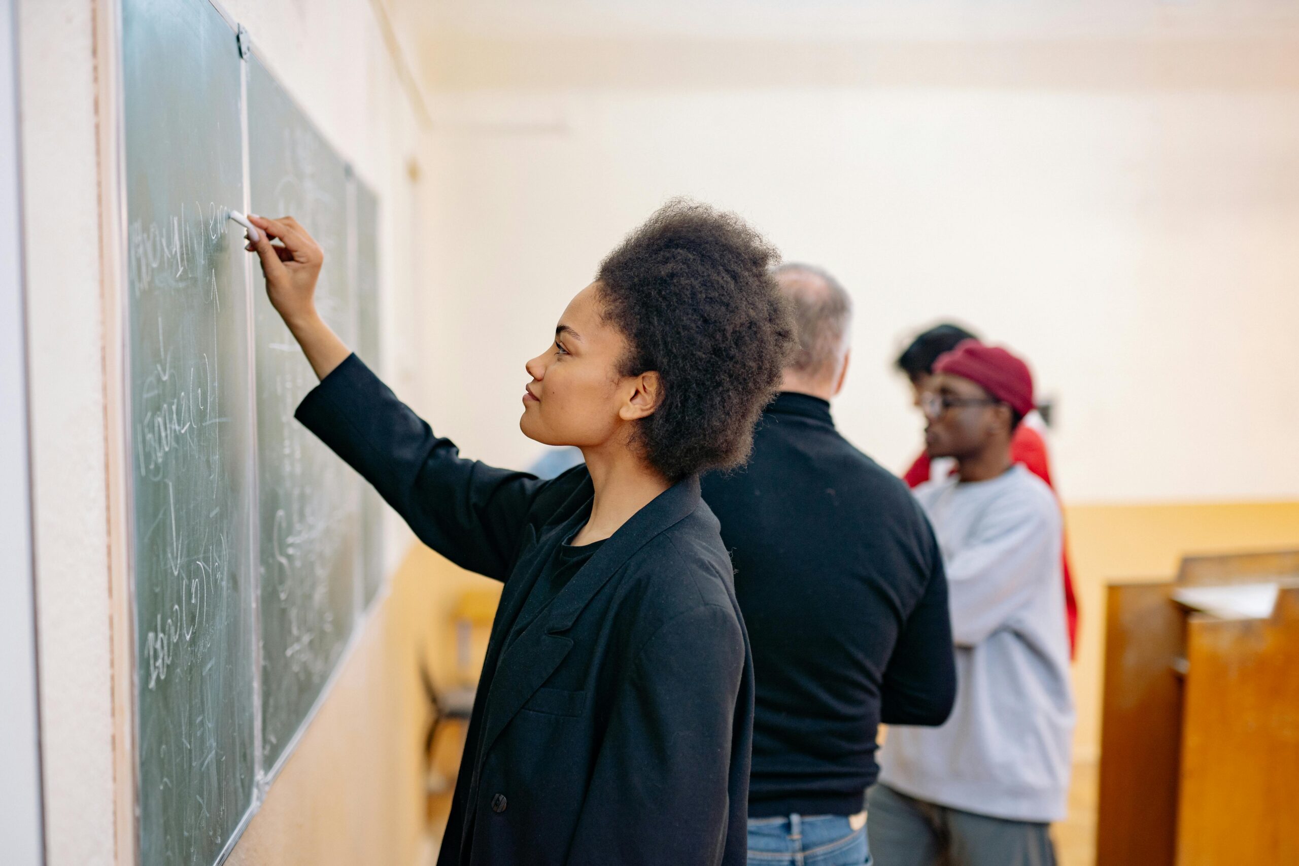 diverse group of colleagues in a classroom, with some writing on the chalkboard
