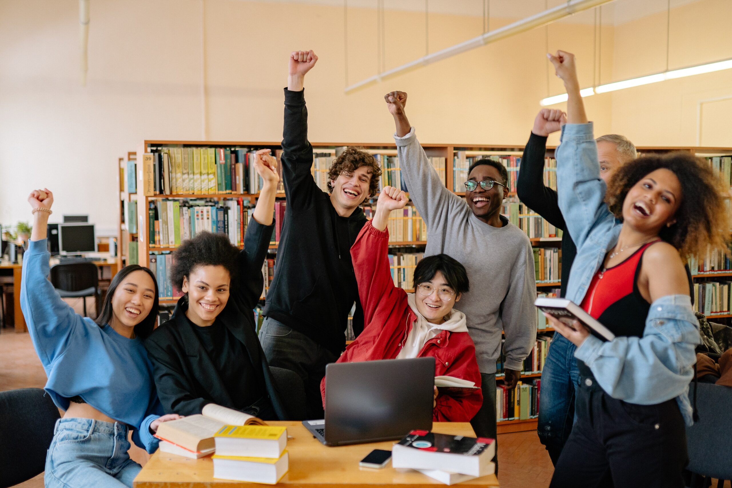 a diverse group of students cheering in a library study space